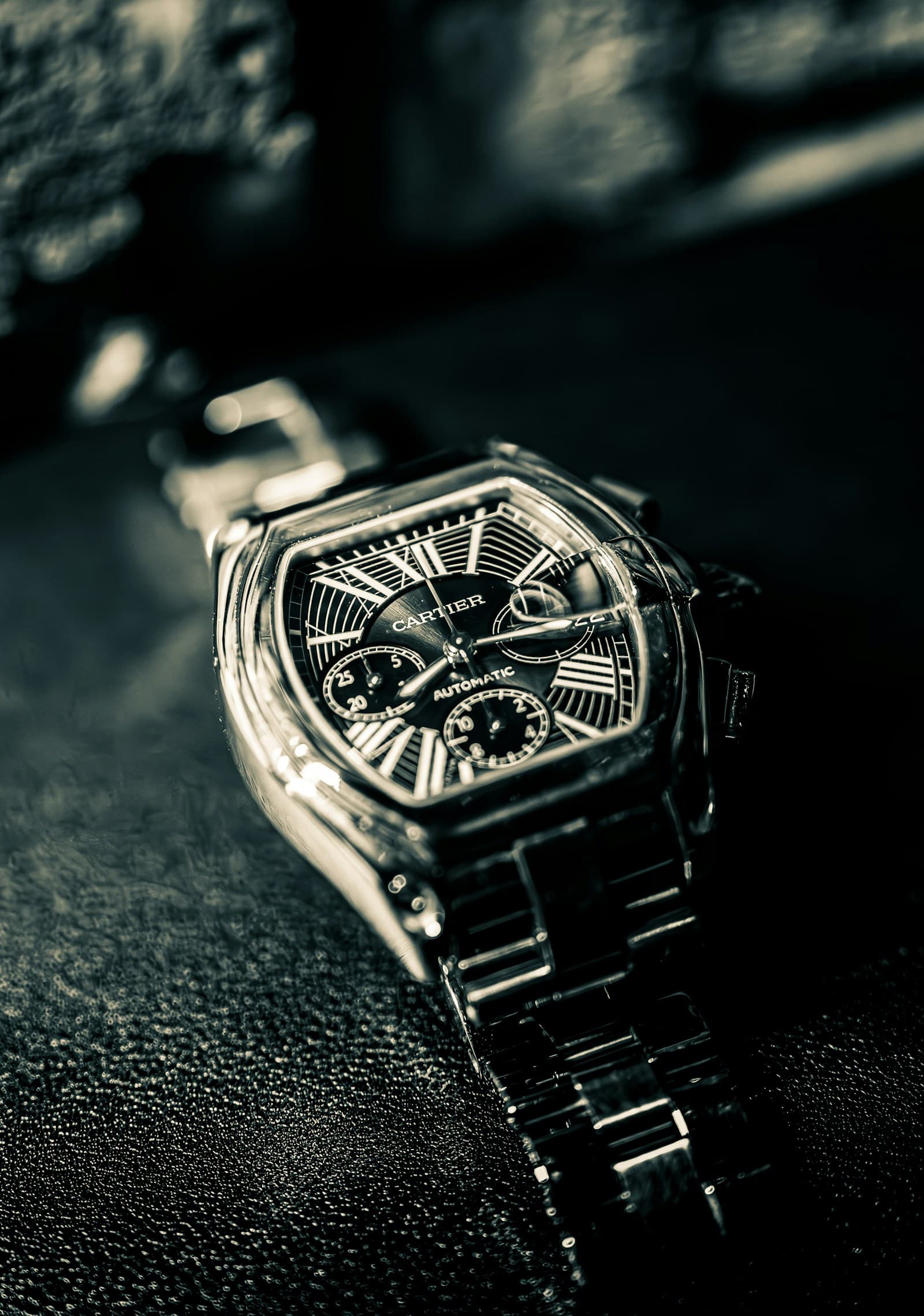 Close-up photograph of a Cartier watch showing Roman numerals, subdials and a polished metal case