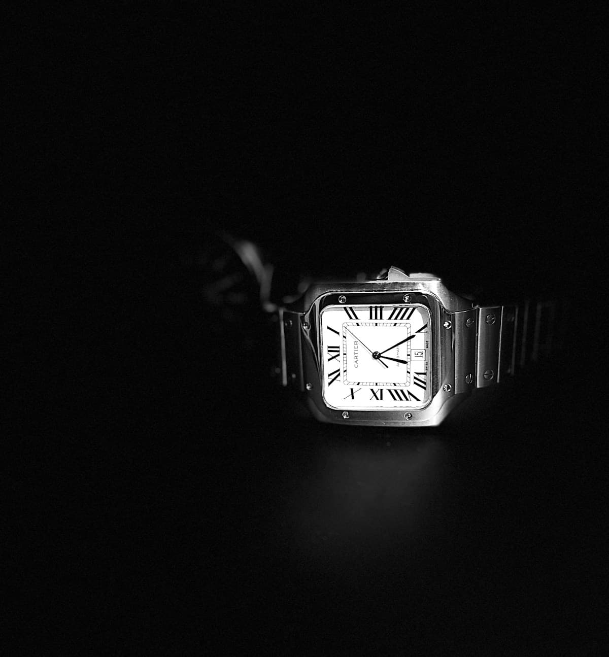 Cartier Santos with a square steel case and Roman numeral dial emerging from a dark background
