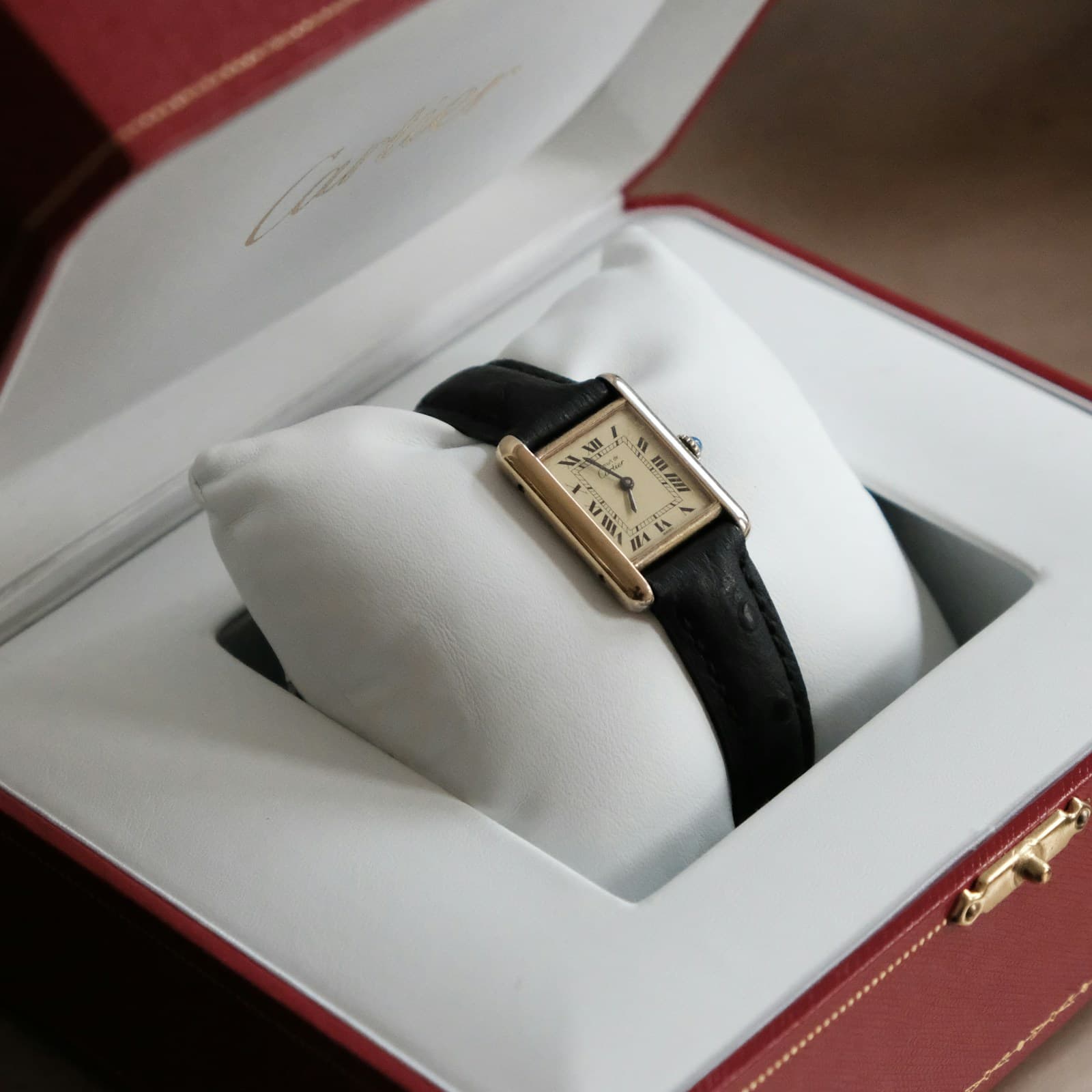 Cartier Tank with a gold-tone rectangular case and black leather strap in its presentation box