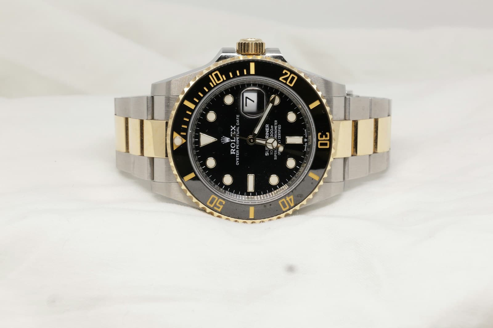Two-tone Rolex Submariner with a black dial and bezel, photographed on light fabric